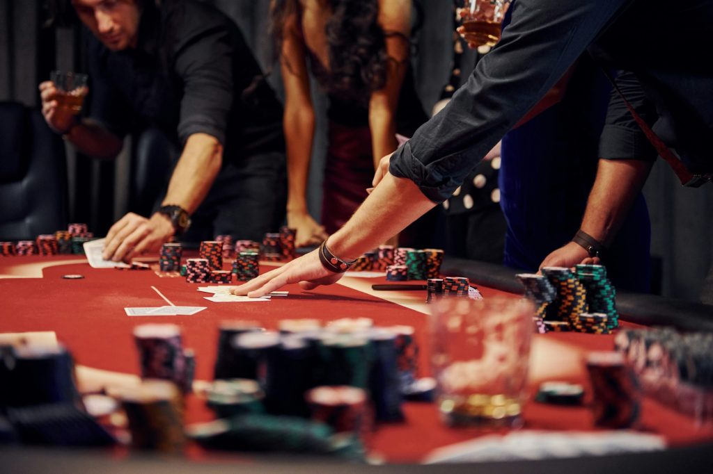 People in elegant clothes standing and playing poker in casino together